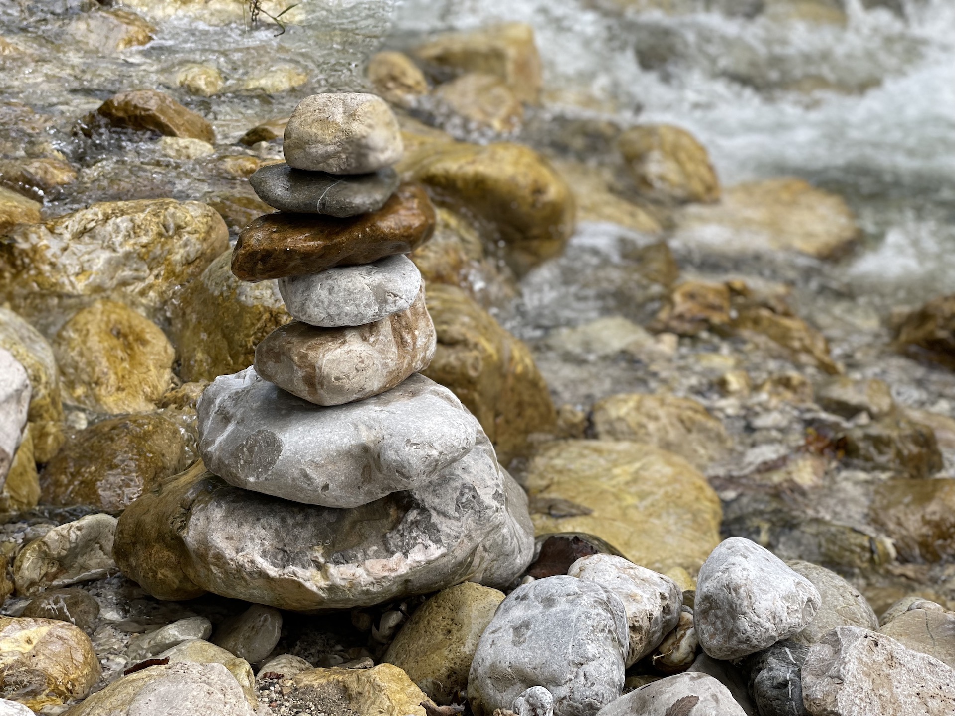 Steinmänchen in einem Fluss. Brauntöne und Grautöne. Bewegtes Wasser